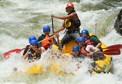 Smiling people having fun white water rafting